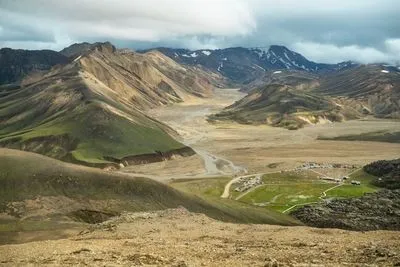 Weiter Blick über das Tal von Landmannalaugar mit Zeltplatz, verzweigtem Fluss und farbigen Bergen